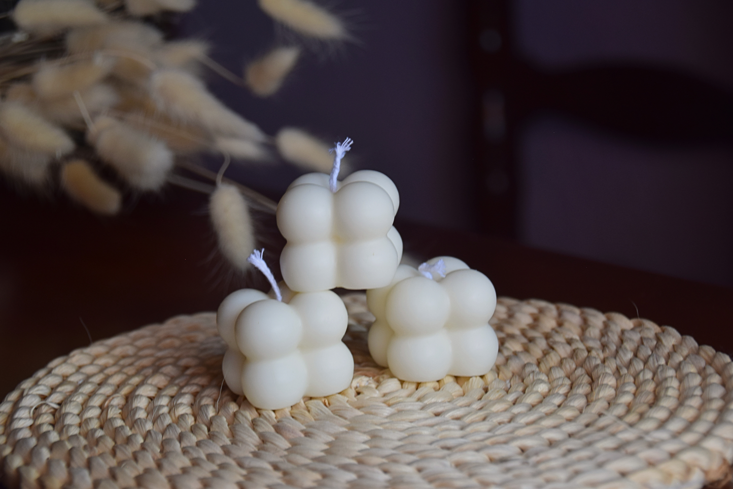 Tres velas quadradas con burbujas y pabilo de algodon con fondo rustico. 