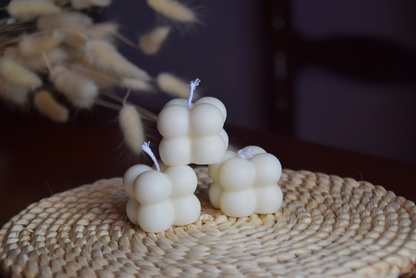 Tres velas quadradas con burbujas y pabilo de algodon con fondo rustico. 