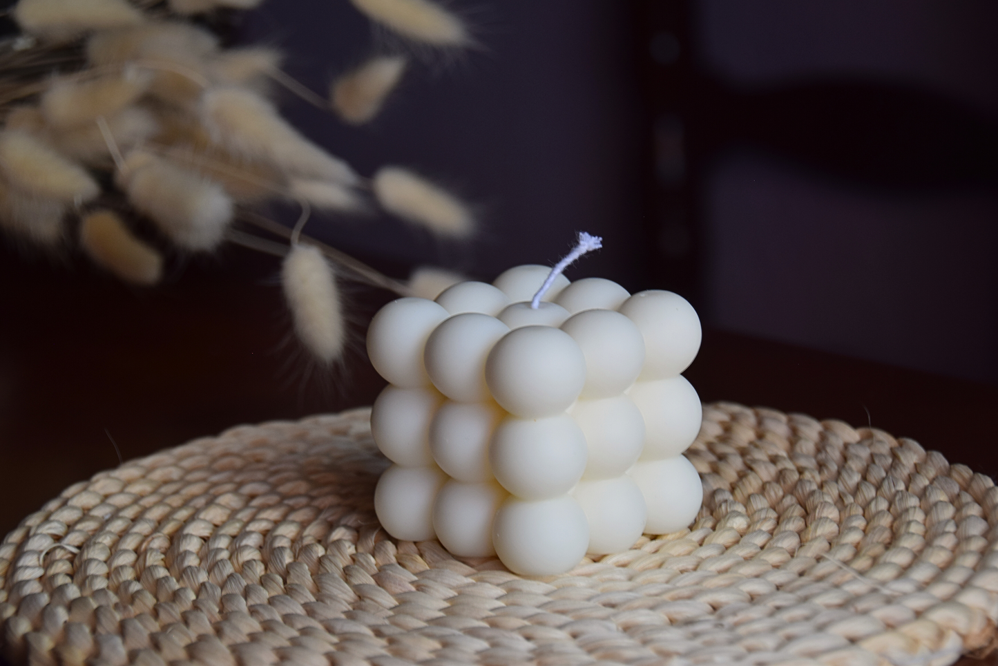 Vela decorativa quadrada con burbujas y pabilo de algodon en fondo rustico.