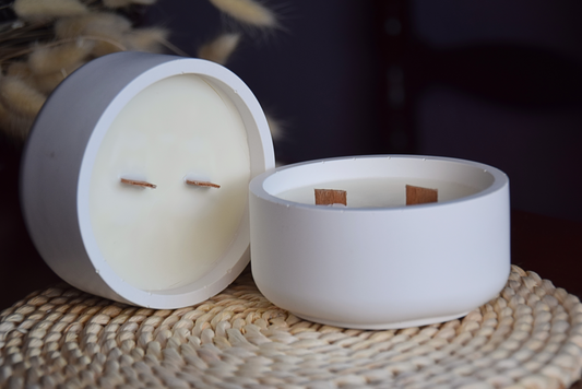 Velas decorativas en cuenco liso con dos mechas de madera en fondo rustico.