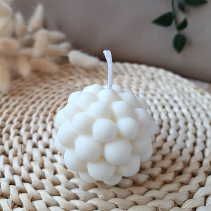Vela decorativa natural de soja con diseño de burbujas estilo moderno y minimalista, sobre base de fibras naturales y fondo neutro