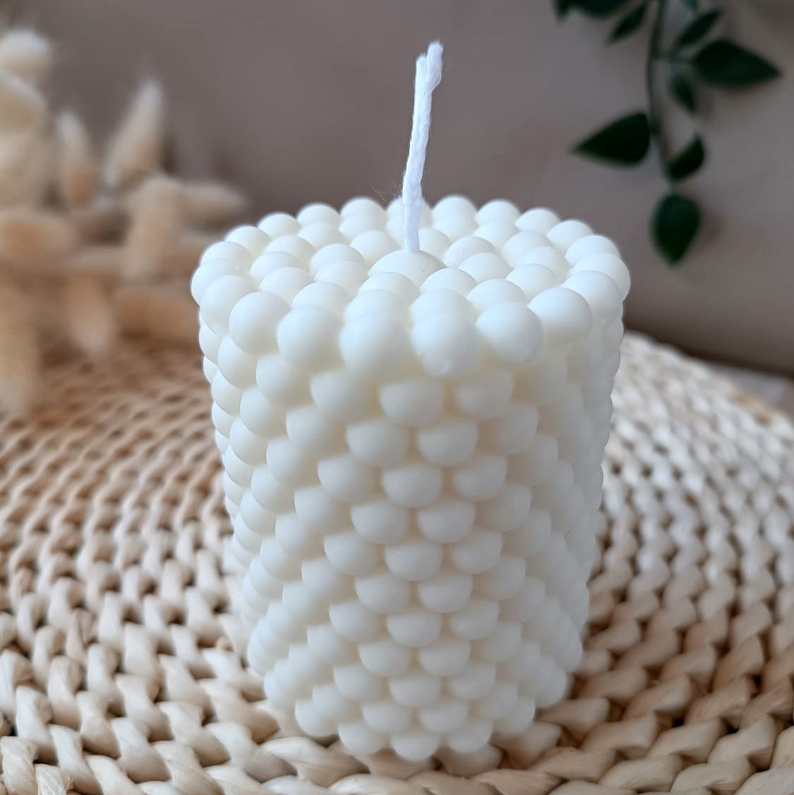 Vela decorativa natural de soja en forma de cono con diseño de burbujas estilo moderno, sobre base de fibras y fondo neutro