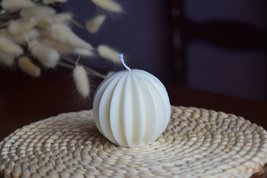 Vela decorativa redonda con forma geometrica y pabilo de algodon en fondo rustico.