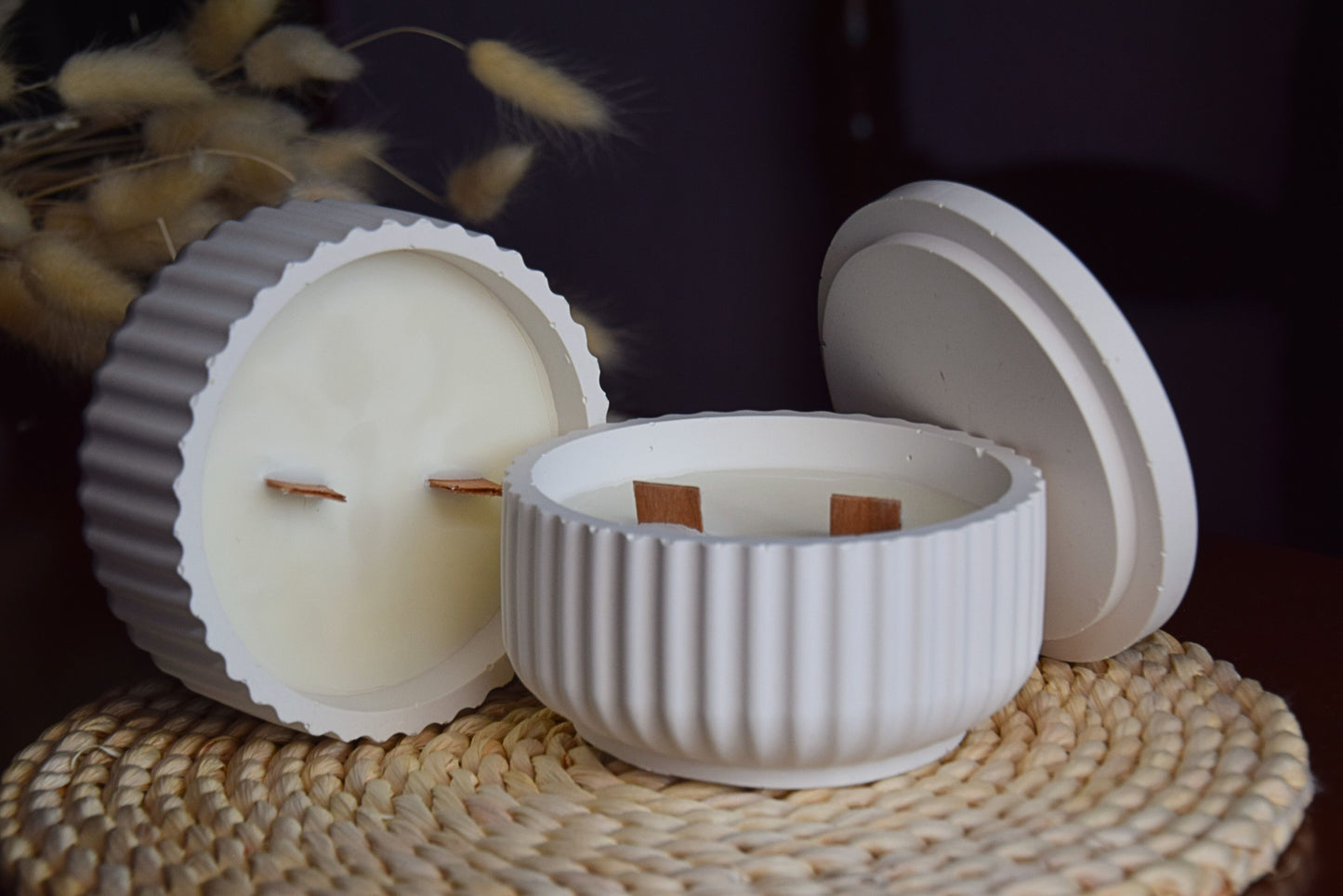 Vela decorativa en cuenco acanalado con mechas de madera en fondo rustico.