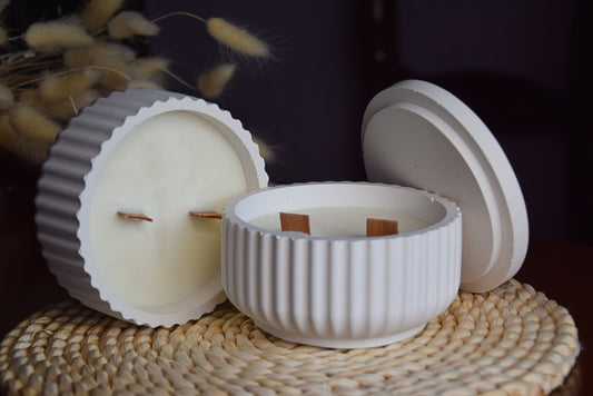 Vela decorativa en cuenco acanalado con mechas de madera en fondo rustico.