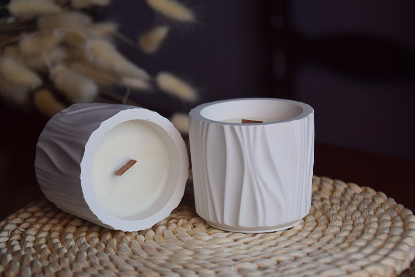 Velas decorativas en recipiente con formas organicas con mecha de madera en fondo rustico.