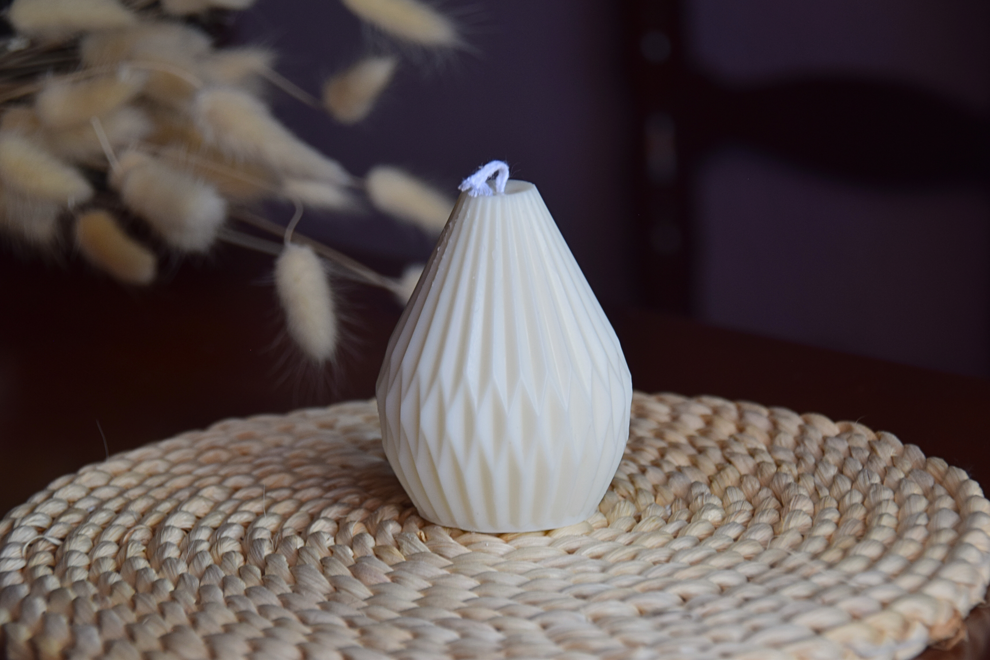 Vela decorativa de soja con formas geometricas y pabilo de algodon en fondo rustico.