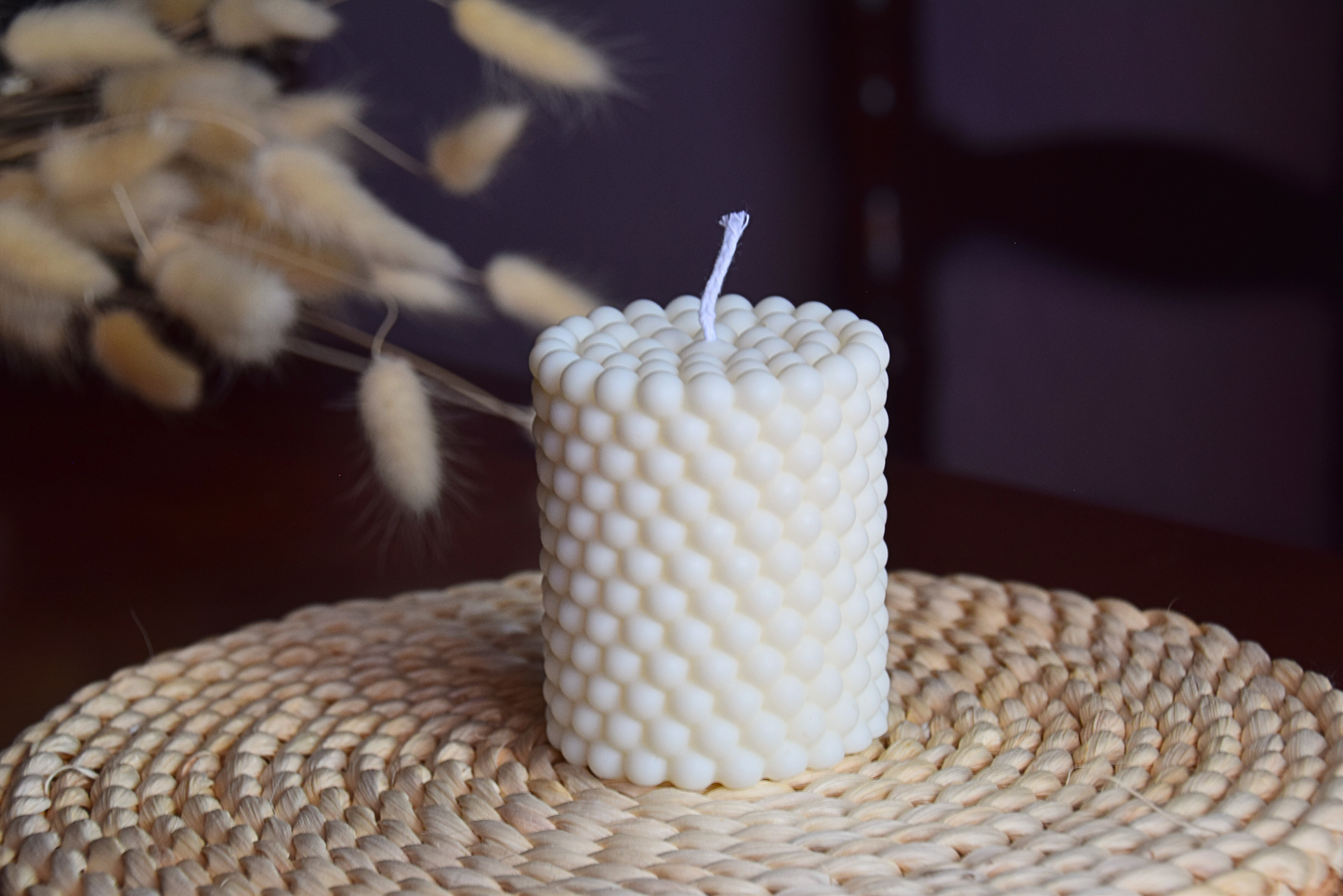 Vela decorativa en forma de pilar con burbujas y pabilo de algodon con fondo rustico. 
