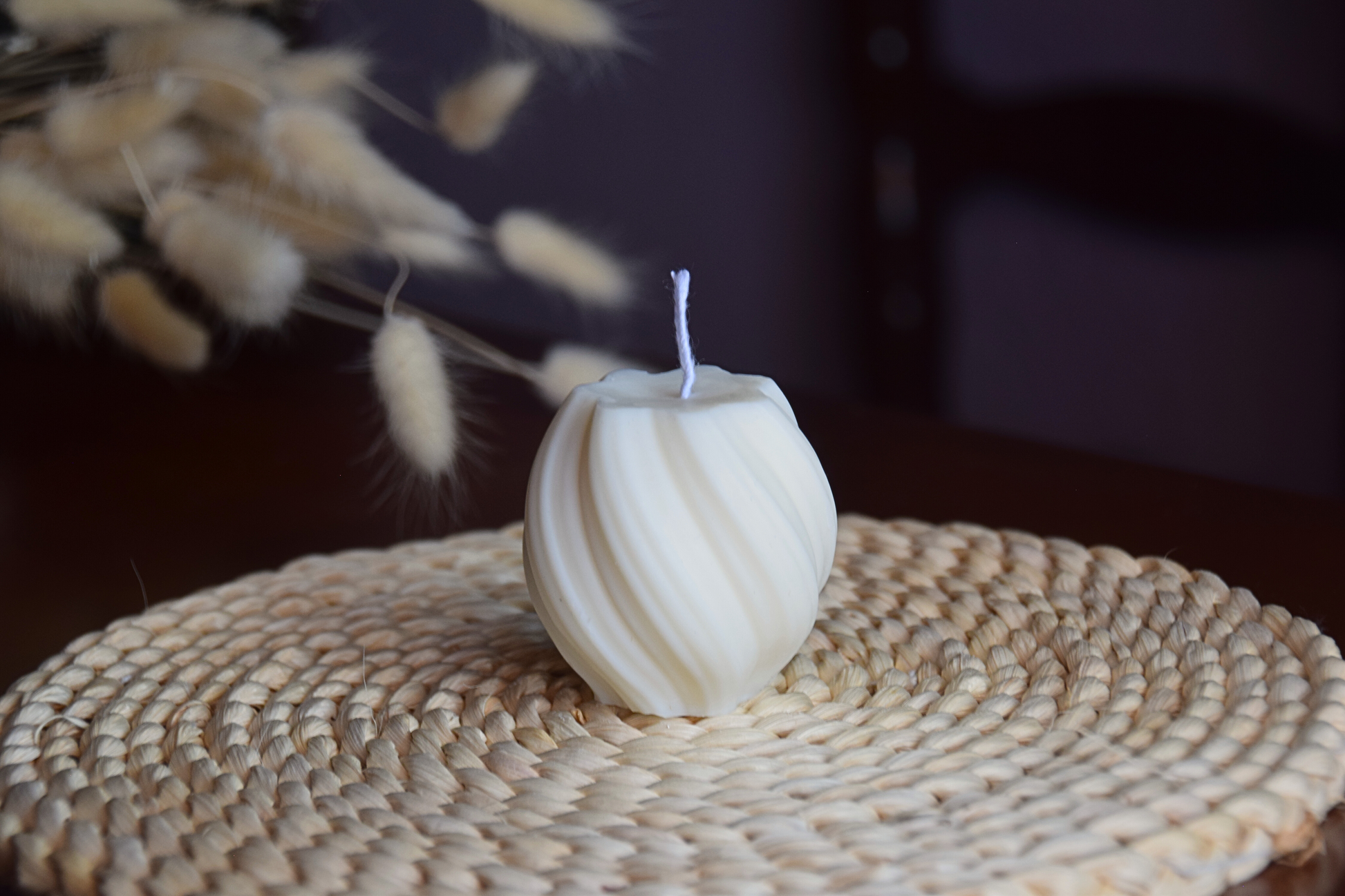 Vela decorativa pequeña en forma de tirabuzon con pabilo de algodon presentada en fondo rustico. 