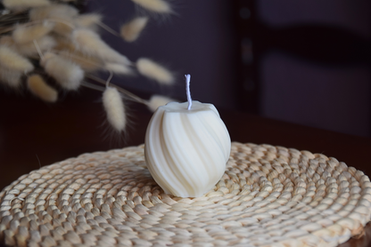 Vela decorativa pequeña en forma de tirabuzon con pabilo de algodon presentada en fondo rustico. 