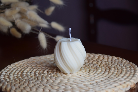 Vela decorativa pequeña en forma de tirabuzon con pabilo de algodon presentada en fondo rustico. 