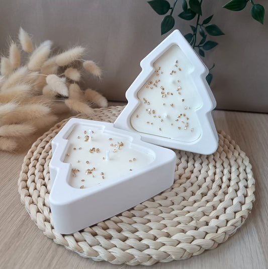 Dos velas de soja en forma de árbol en recipiente blanco de resina mineral con decoración dorada sobre base de fibras naturales y fondo neutro