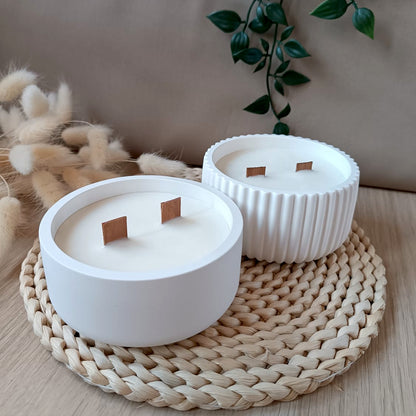 Conjunto de velas decorativas de soja en recipiente de resina mineral liso y acanalado con doble mecha de madera sobre base de fibras naturales y fondo neutro