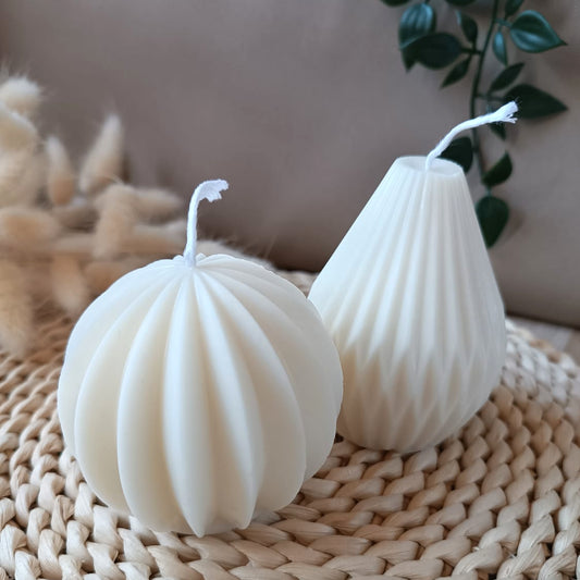 Conjunto de velas decorativas de soja con diseño geométrico en forma esférica y cónica sobre base de fibras naturales con fondo neutro