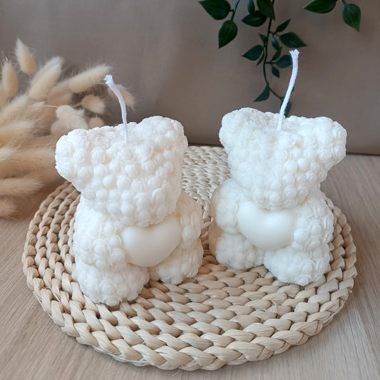 Dos velas artesanales de soja en forma de osito con corazón sobre base de fibras naturales estilo nórdico