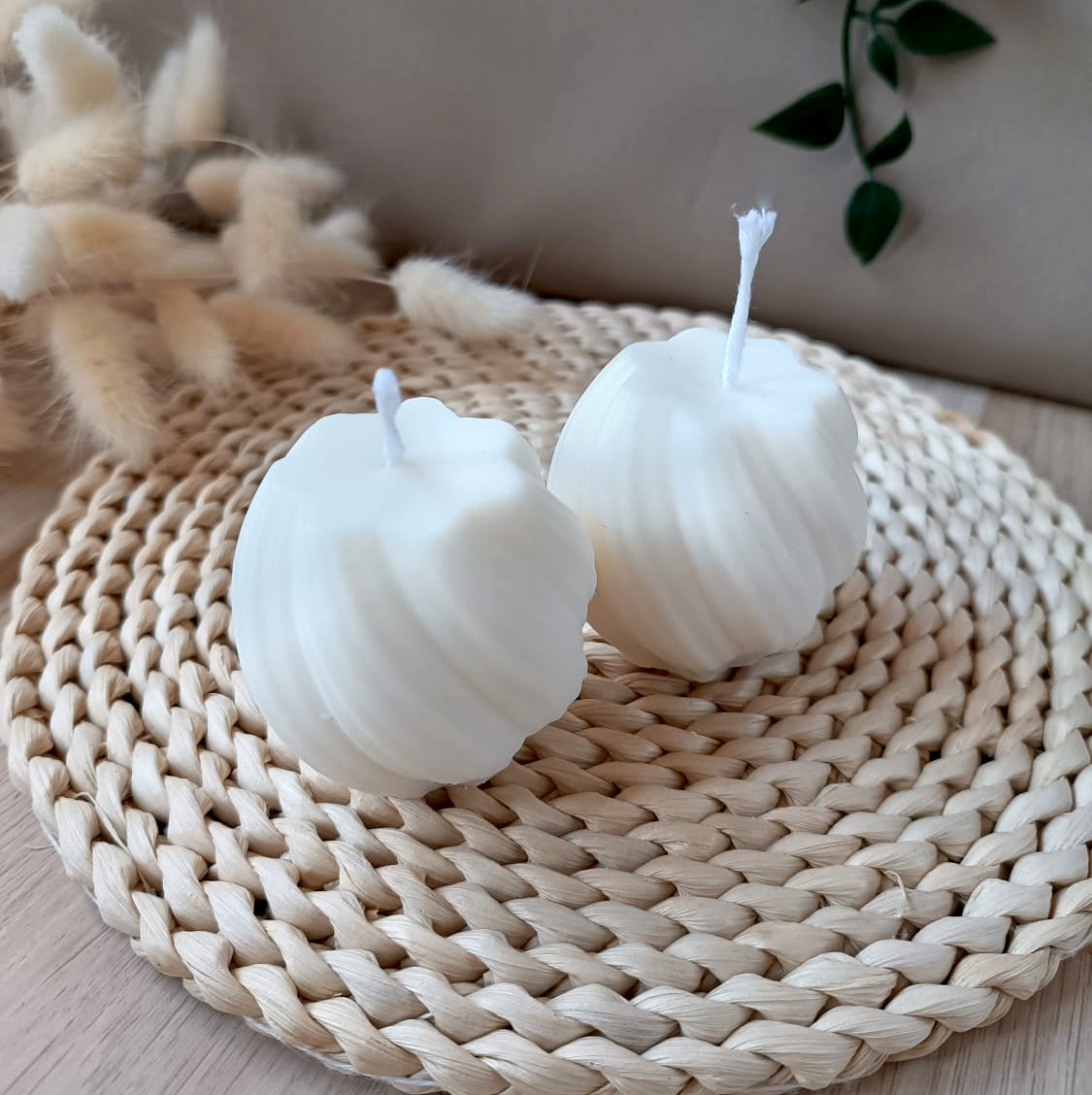 Dos velas artesanales de soja redondas con diseño en espiral sobre base de fibras naturales